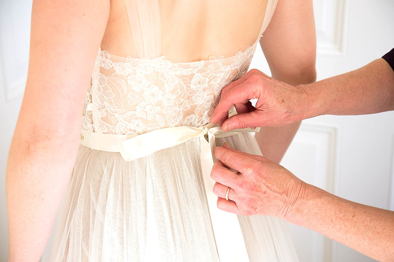 bride being helped into wedding dress