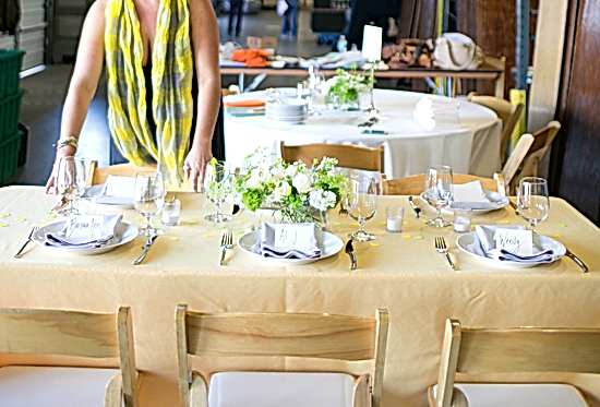 A woman sets a dining table for wedding rentals.