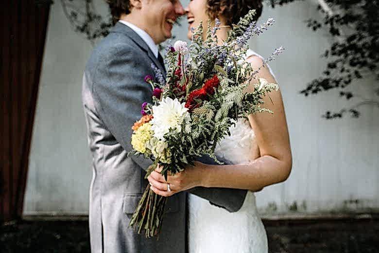couple smiling with wedding flowers