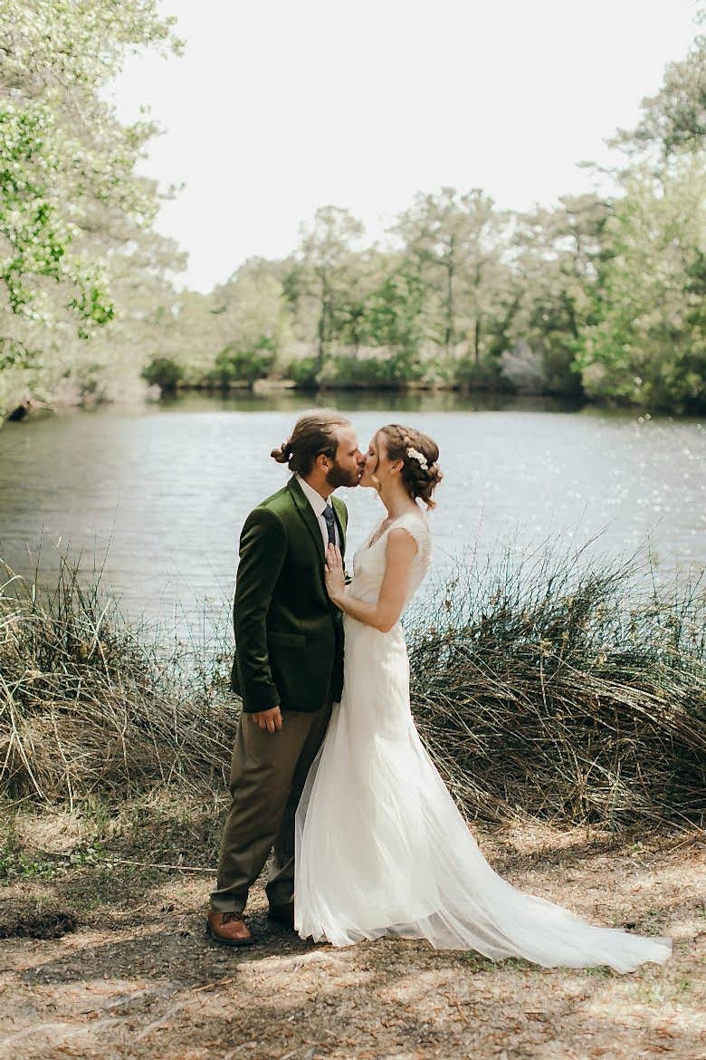 married couple kissing outside in front of a pond