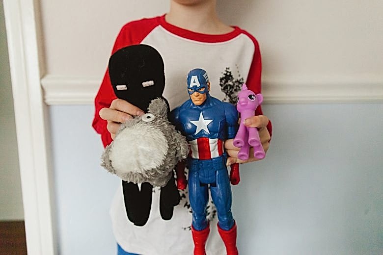 kid's torso with stuffed animals and action hero dolls and pony dolls
