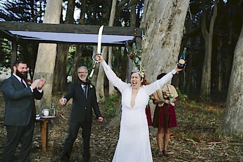 bride holding a sword and bottle of wine
