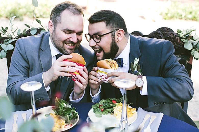 two grooms eating burgers on their wedding day