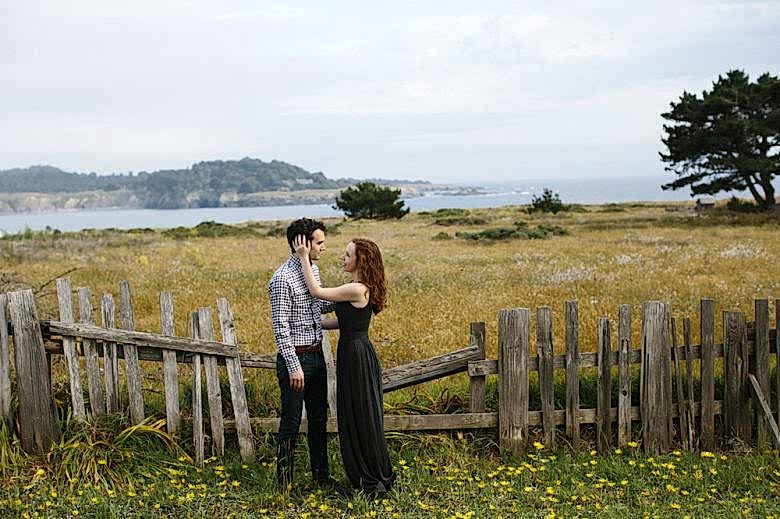 man and woman in field in front of fence
