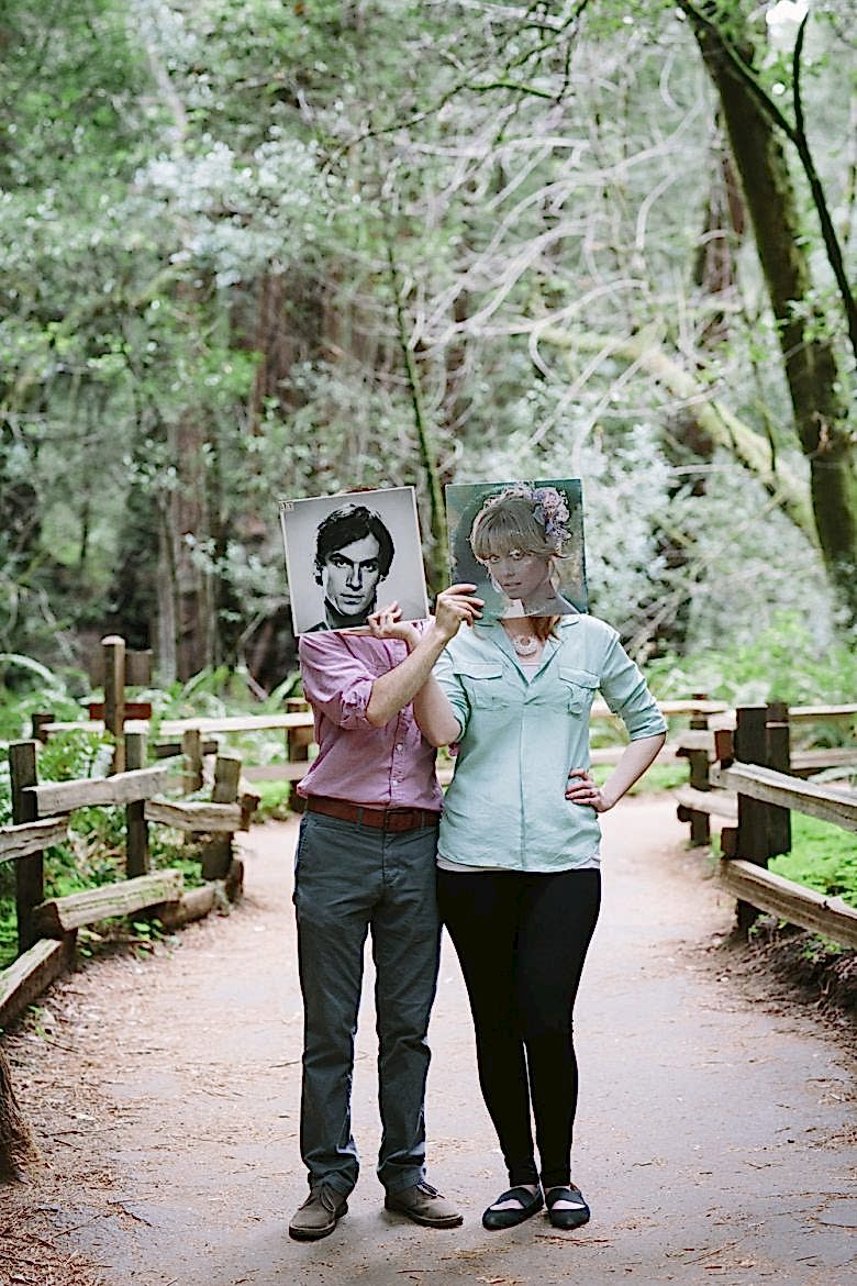 engaged couple holding records over one another's faces
