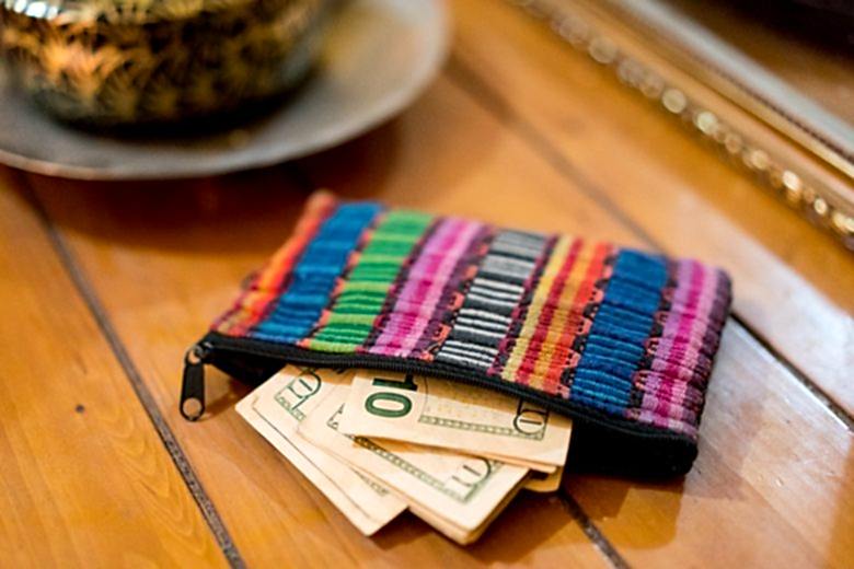 Multi-colored textile wallet with ten dollar bills sticking out