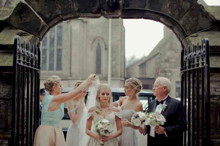 A bride's parents and friends fix her veil before going down the aisle