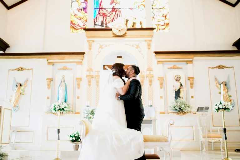 A bride and groom kiss at the altar