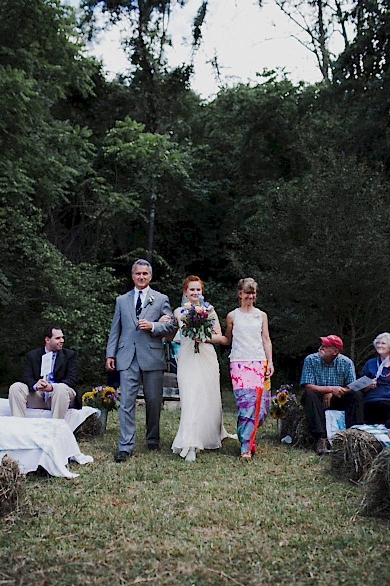 bride walking down wedding aisle with mother and father