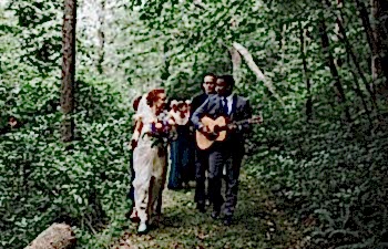 groom playing acoustic guitar and walking with bride