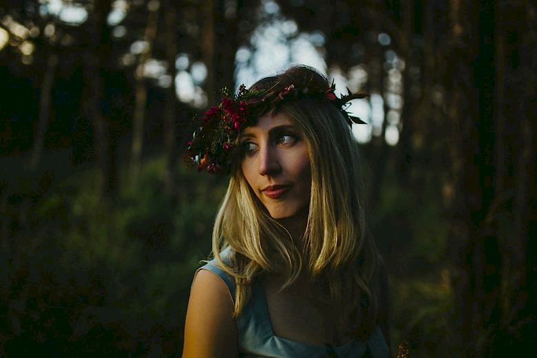 Woman wearing floral crown standing in forest