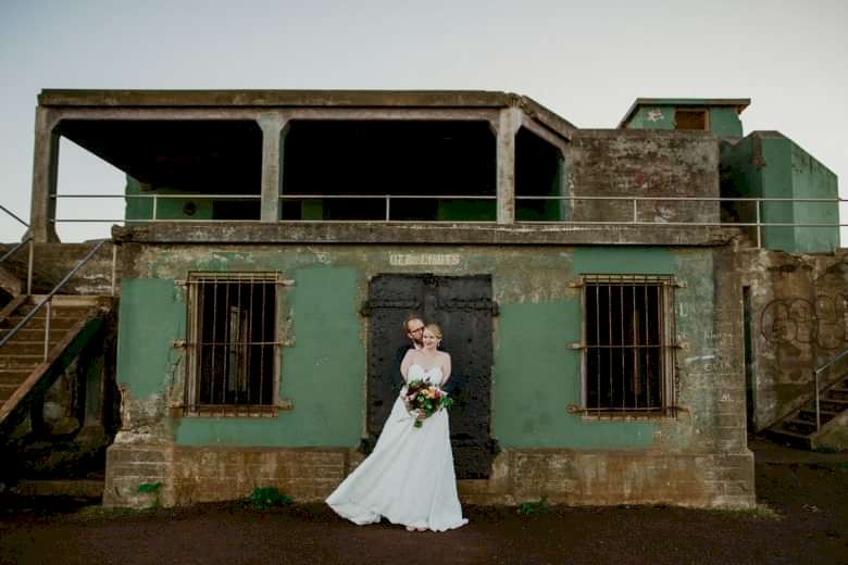 bride and groom standing outside green building