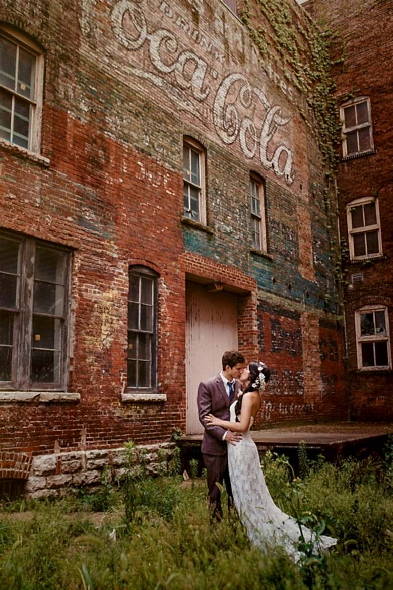 couple standing in front of a brick coca cola sign
