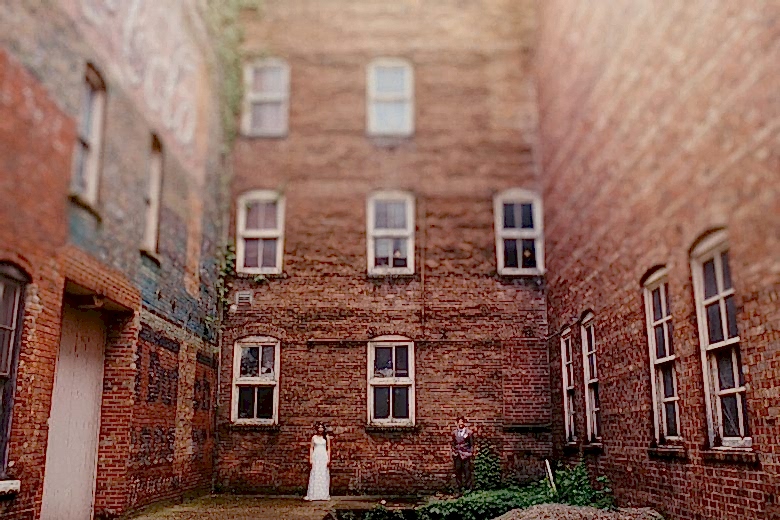 bride and groom standing in front of a brick wall