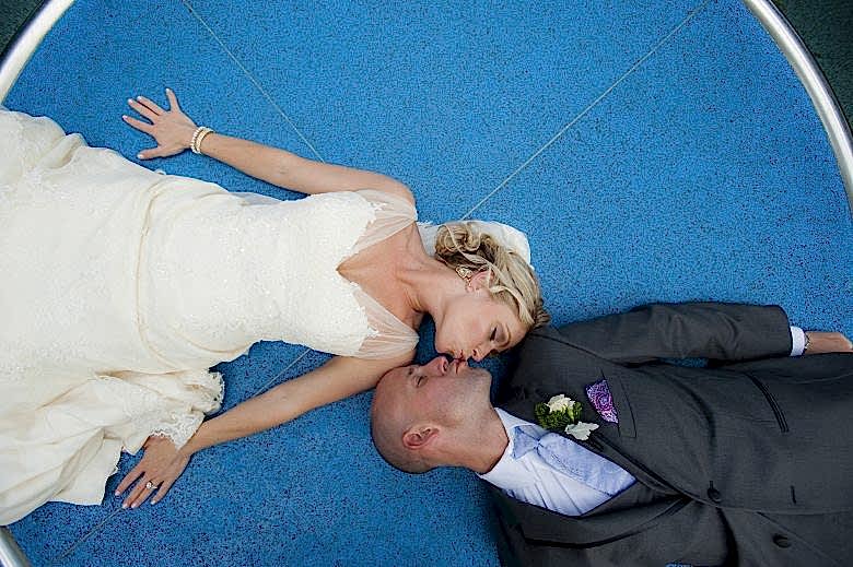 bride and groom kissing while laying down