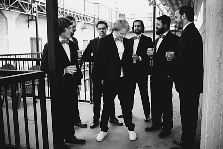 black and white groomsmen surrounding groom