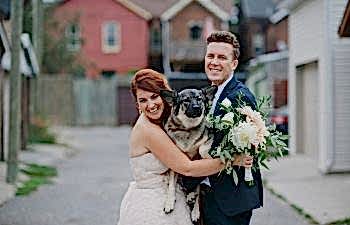 bride and groom holding dog on wedding day