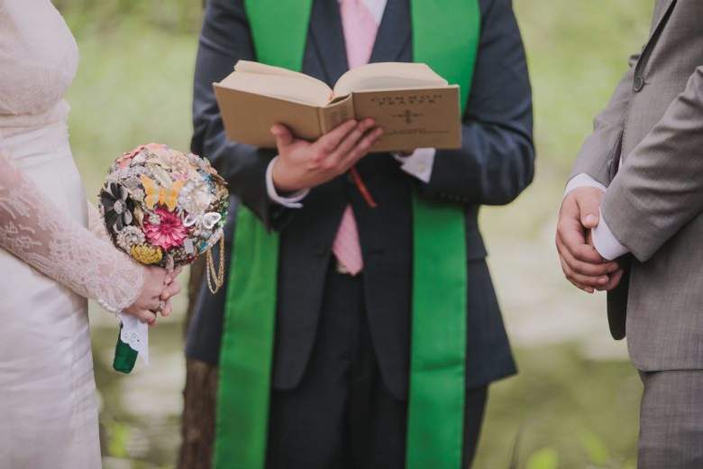 bride with brooch bouquet and groom with officiant at altar
