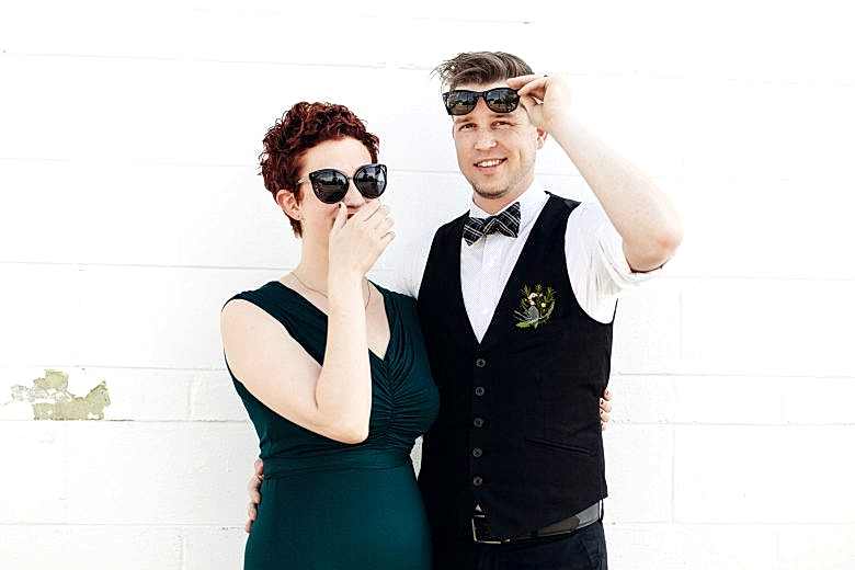 Bride in a green dress and a groom laughing after eloping