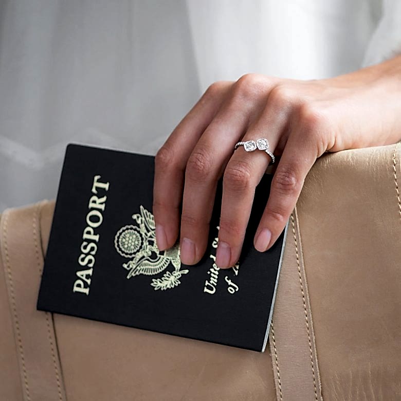 two stone unique diamond engagement ring on the hand of a woman holding a passport