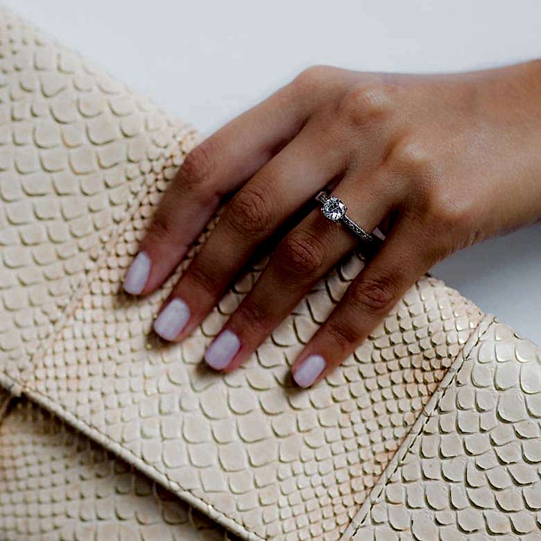 woman holding a purse wearing a simple solitaire engagement ring