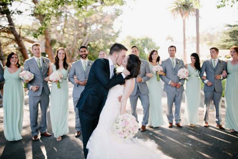 bride and groom kissing in front of wedding party