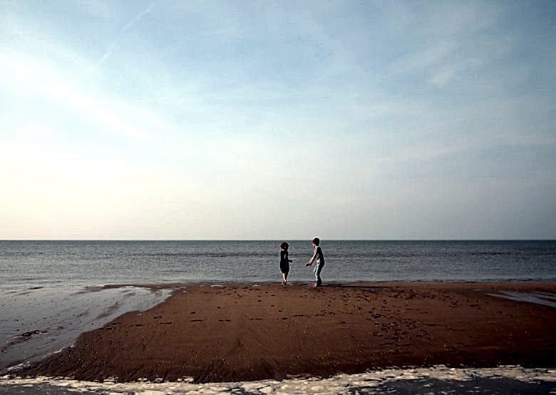 two children playing by the ocean