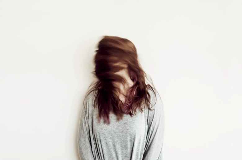 woman shaking head in front of a wall