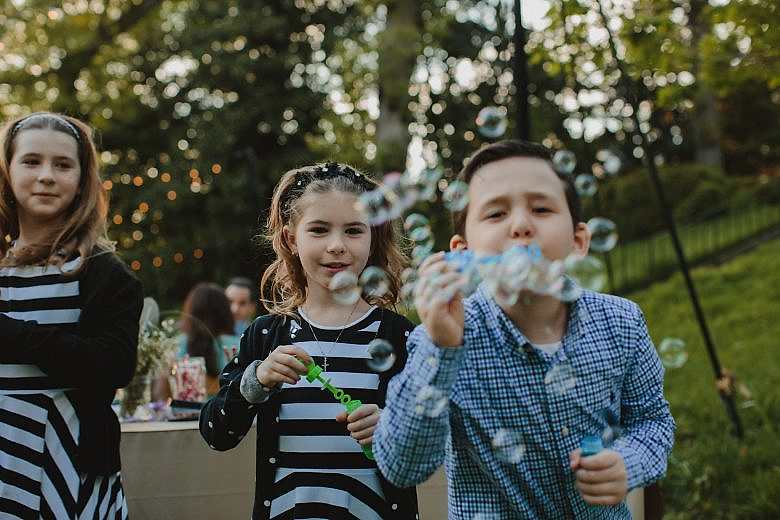 kids blowing bubbles at a camera