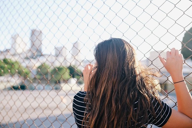woman standing against a fence