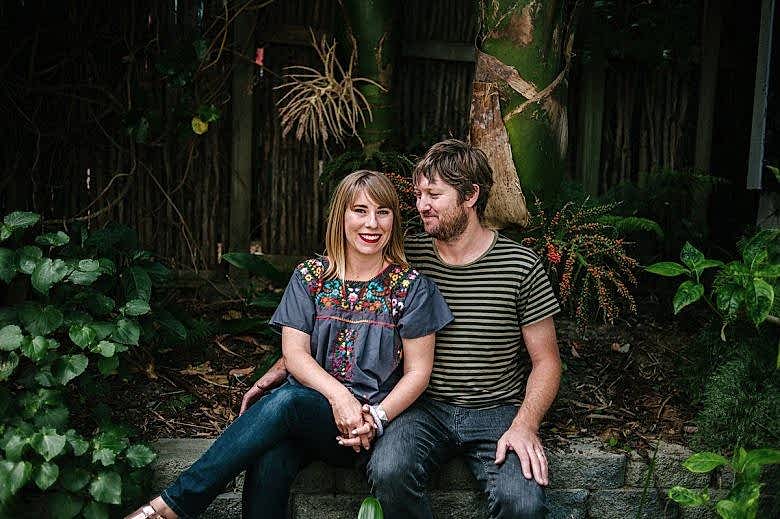 couple smiling sitting beneath a tree with a wedding ring from ash hilton
