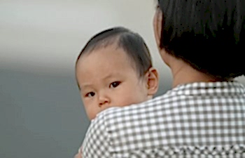 a baby looking over a woman's shoulder
