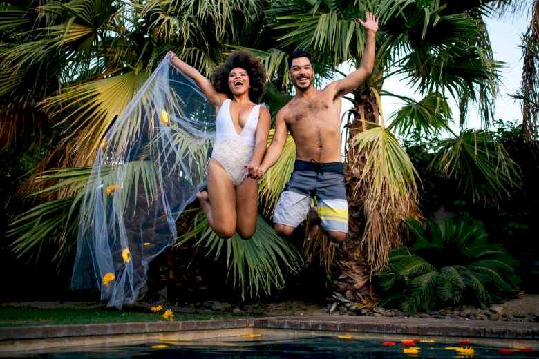 a couple jumping into a pool and holding hands