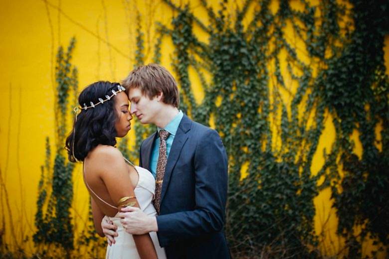 a couple standing together on a yellow wall