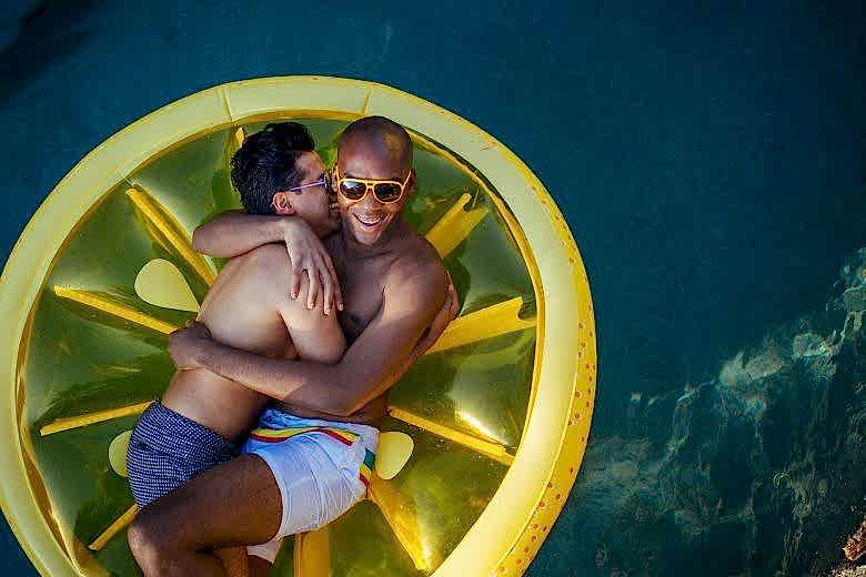 two men snuggling on a pool float