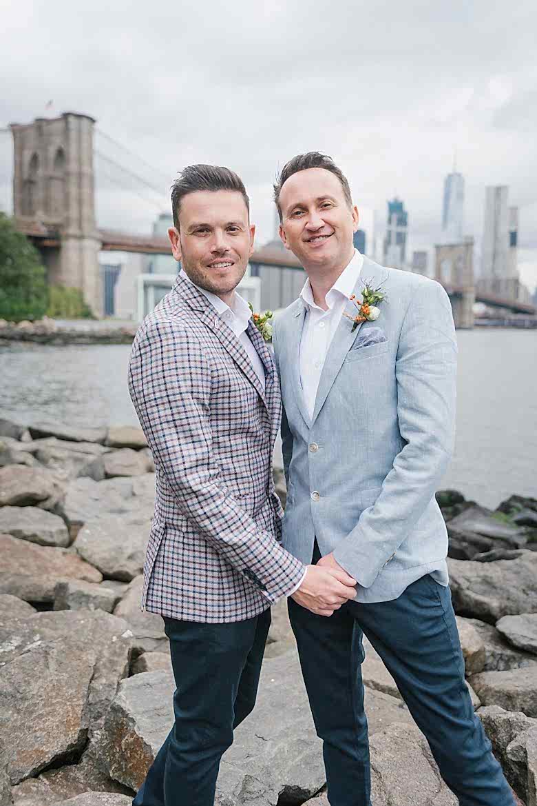 portrait of two grooms in front of Brooklyn Bridge and Manhattan skyline