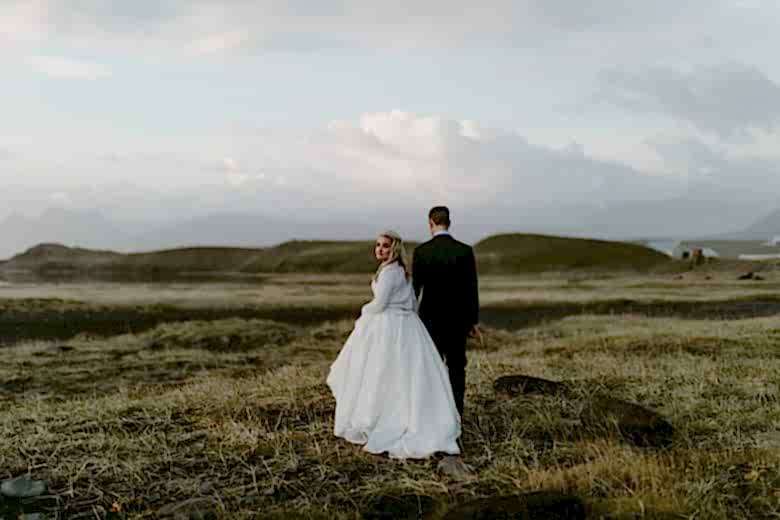 Bride and groom in field in Fjaðrárgljúfur