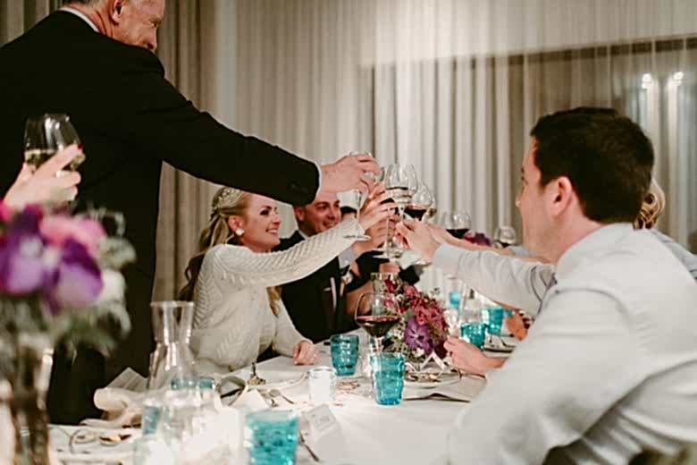 Bride, groom, and guests toasting at wedding dinner reception