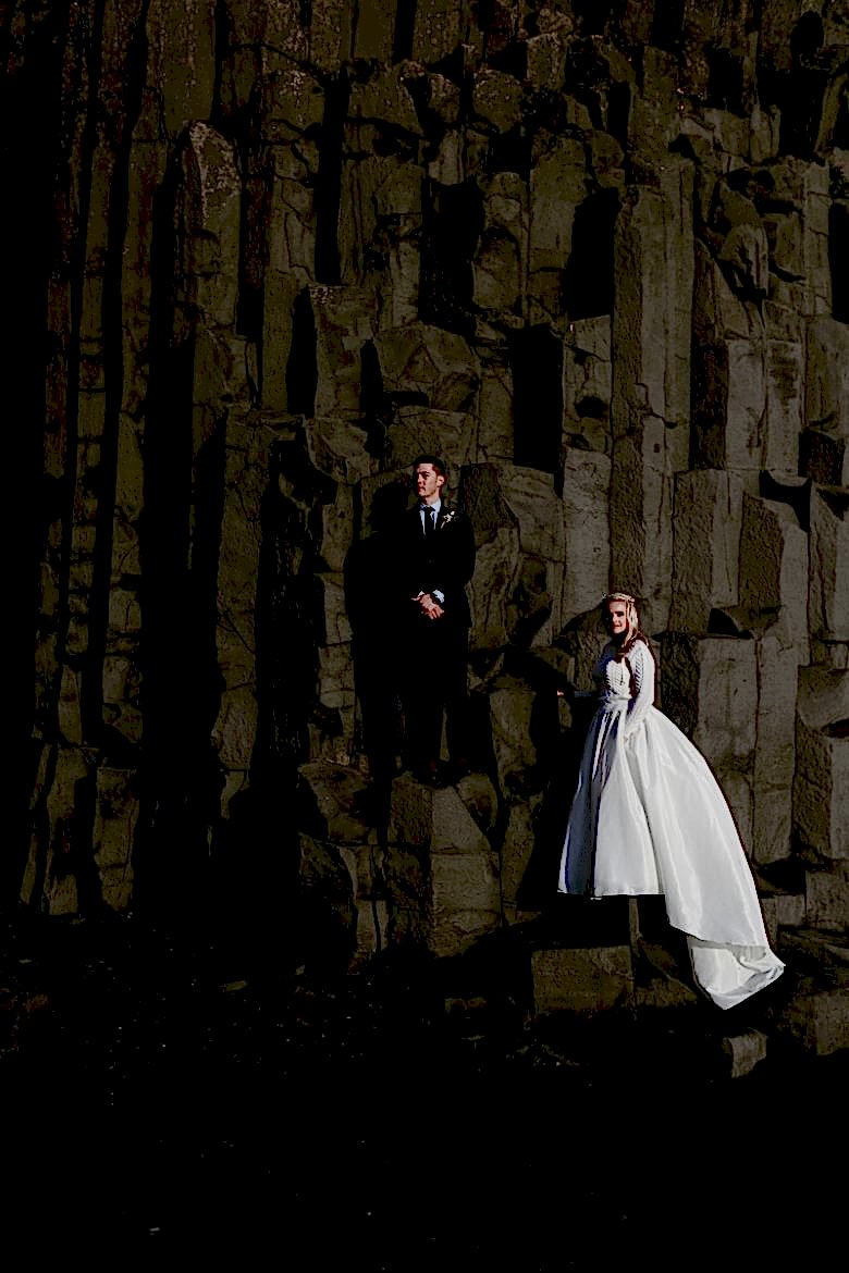 Bride and groom in front of rocky cliff in Fjaðrárgljúfur