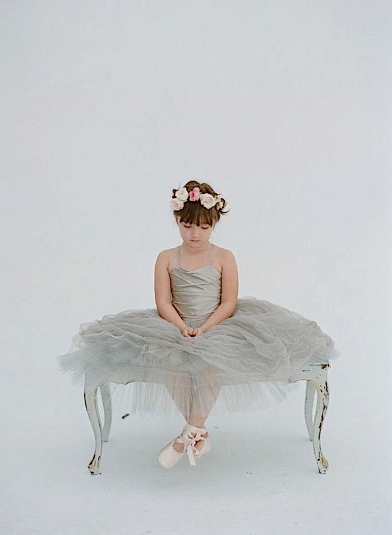 little girl with a flower crown sitting on a bench in a grey tulle dress