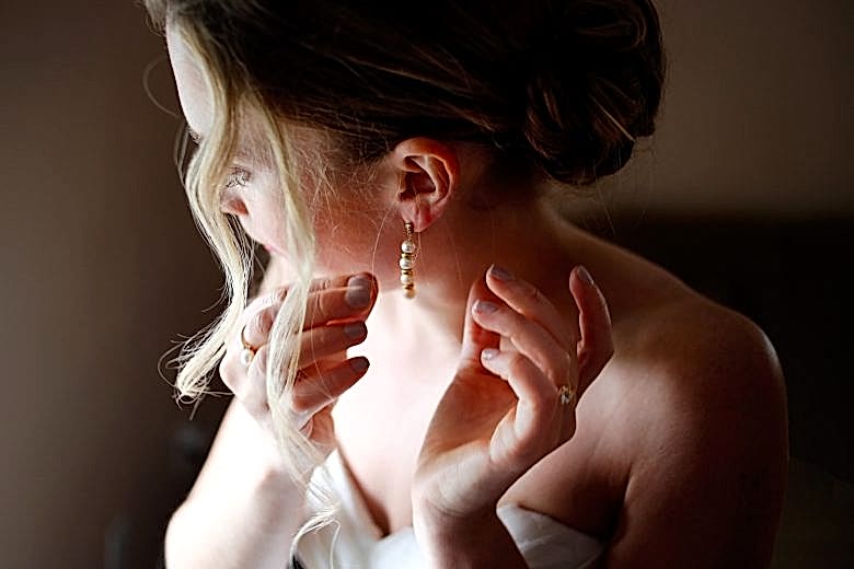 Bride putting on earrings