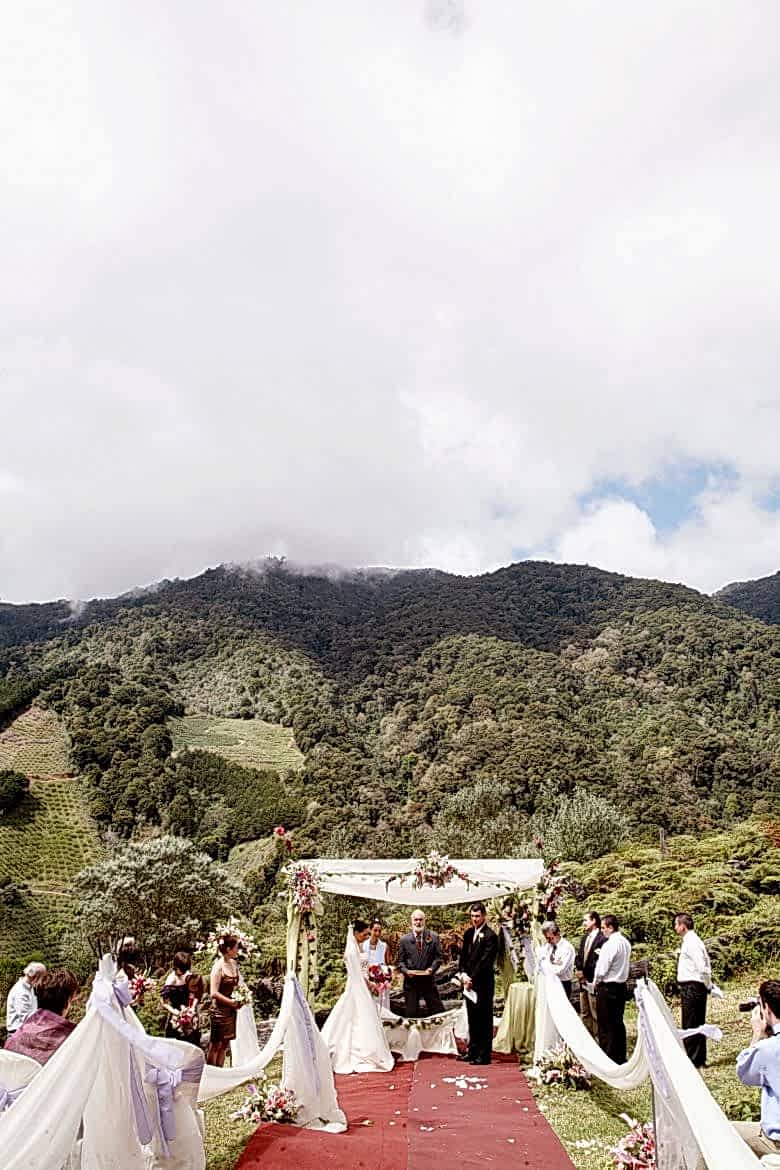 outdoor wedding ceremony under canopy, at base of green mountain