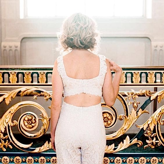 woman in white lace pants and crop top from behind with short wavy blond hair