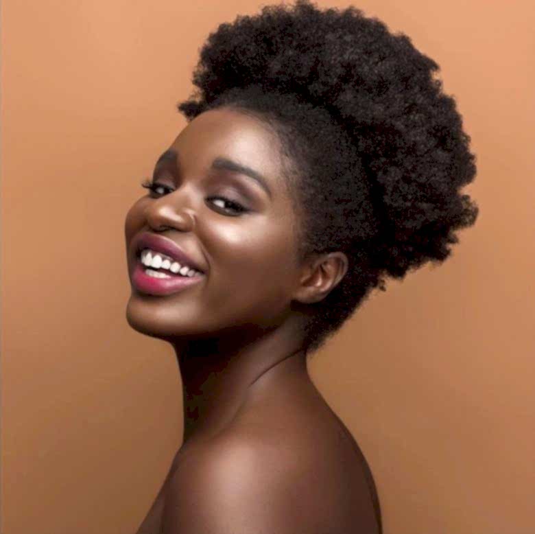 An African American woman looks radiant and smiles back at the camera