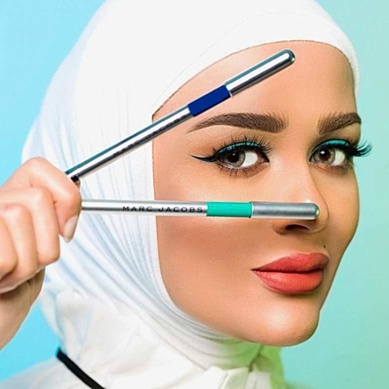 A woman holds two makeup pens looking through them 