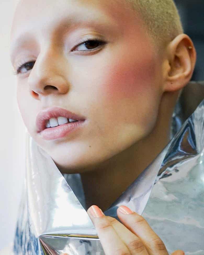 A woman with short hair looking at the camera wearing blush