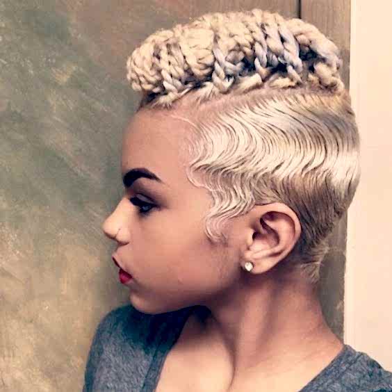 Woman with platinum hair in mohawk with finger waves along the sides, with long hair on top in many twists folded together tightly 