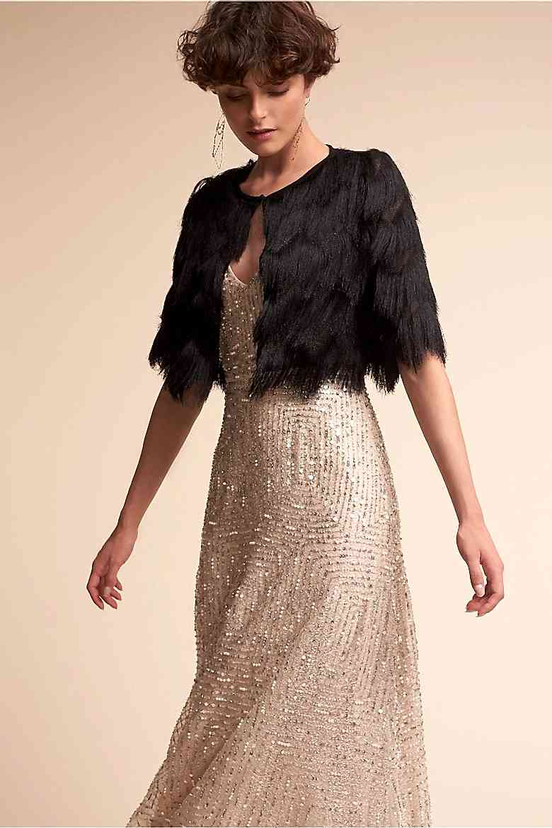 A bride stands tall wearing a dark colored waist level jacket