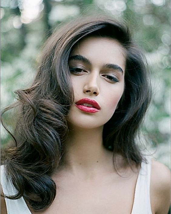 woman with dark hair with very deep side part and romantic voluminous curls