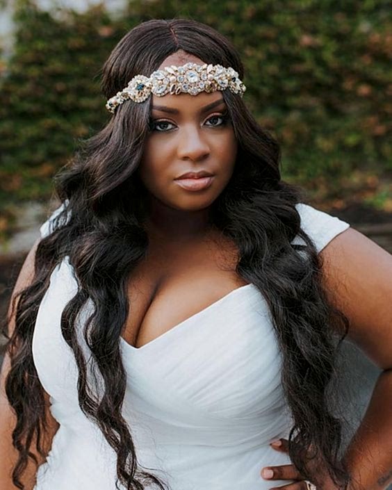 woman with long curled dark hair parted in the middle with ornate jeweled headband across forehead